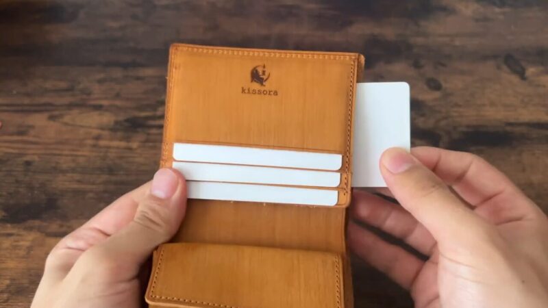 kissora(キソラ)サビアシリーズ二つ折り財布の隠しカードポケットから取り出すシーン